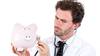 croppedCloseup portrait, young curious male man healthcare professional, doctor, nurse listening to piggy bank with stethoscope. Medical